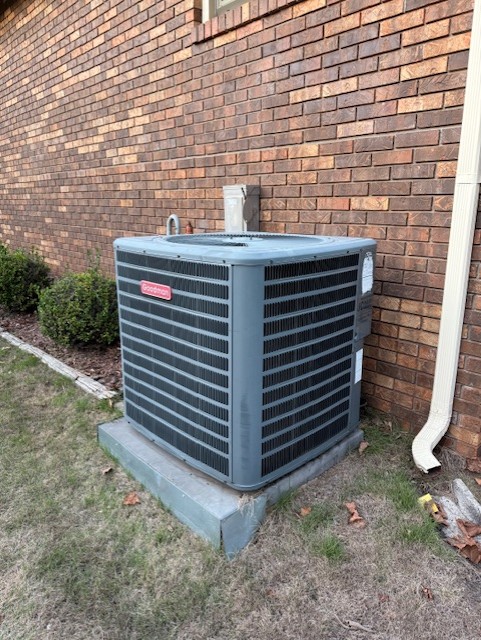 A heat pump installed next to a red brick wall